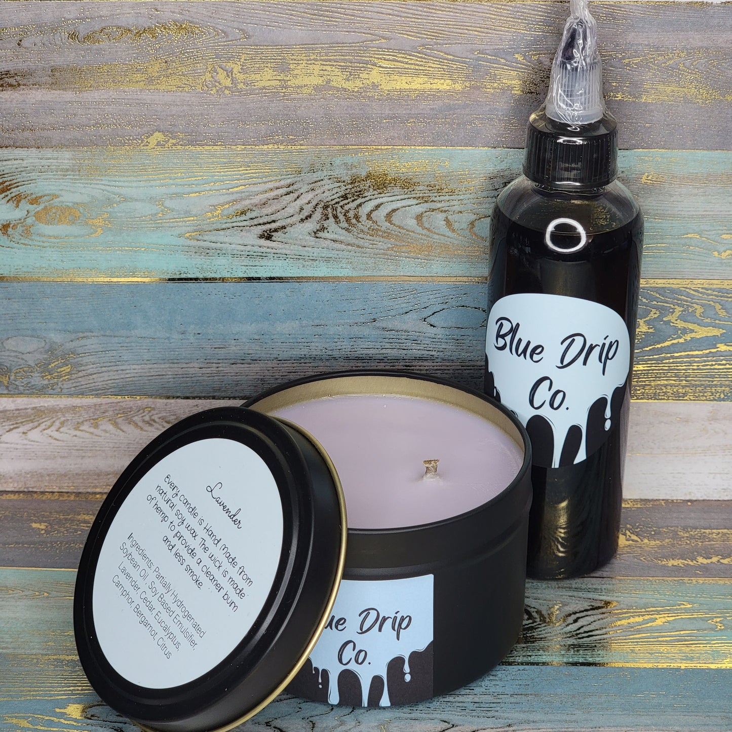 A black candle jar and a bottle labeled 'Blue Drip Co.' on a wooden background.