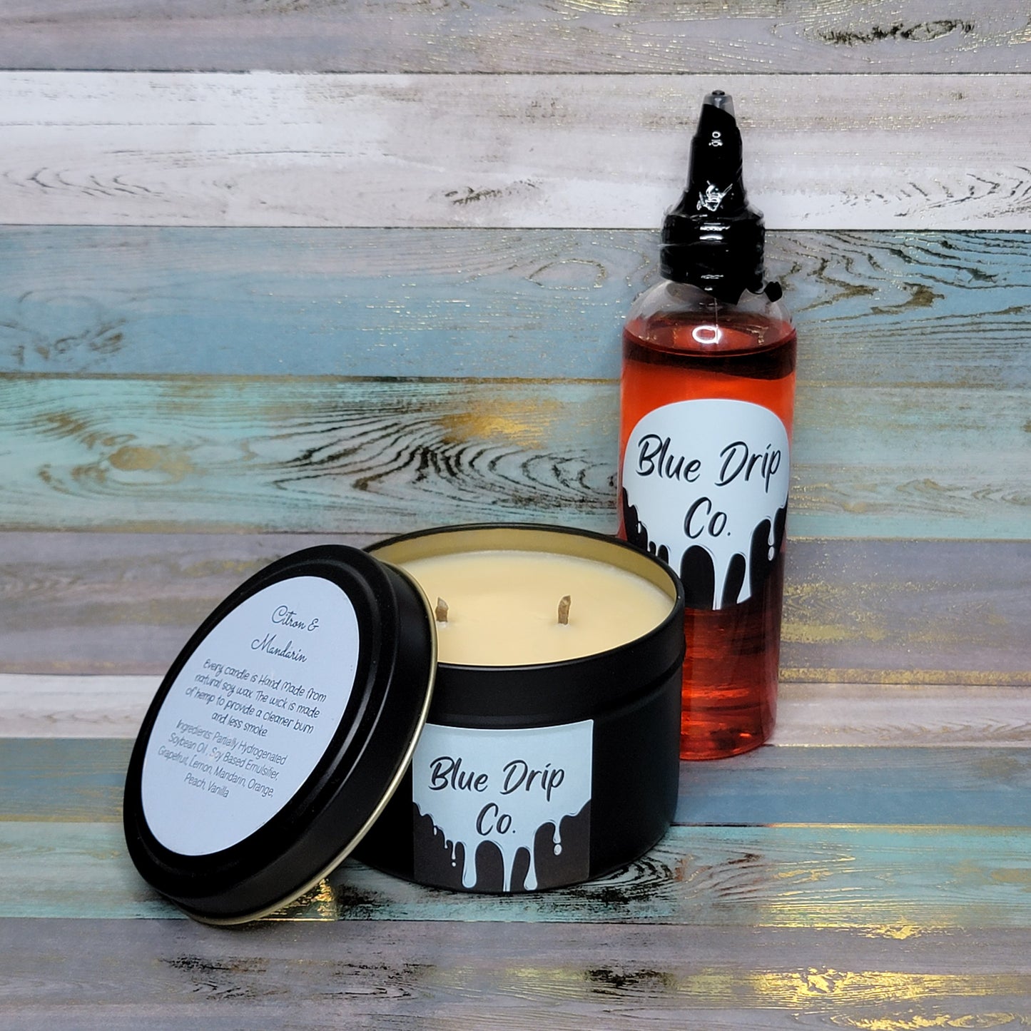 A black candle with a lid and a red bottle labeled 'Blue Drip Co', placed on a colorful wooden surface.