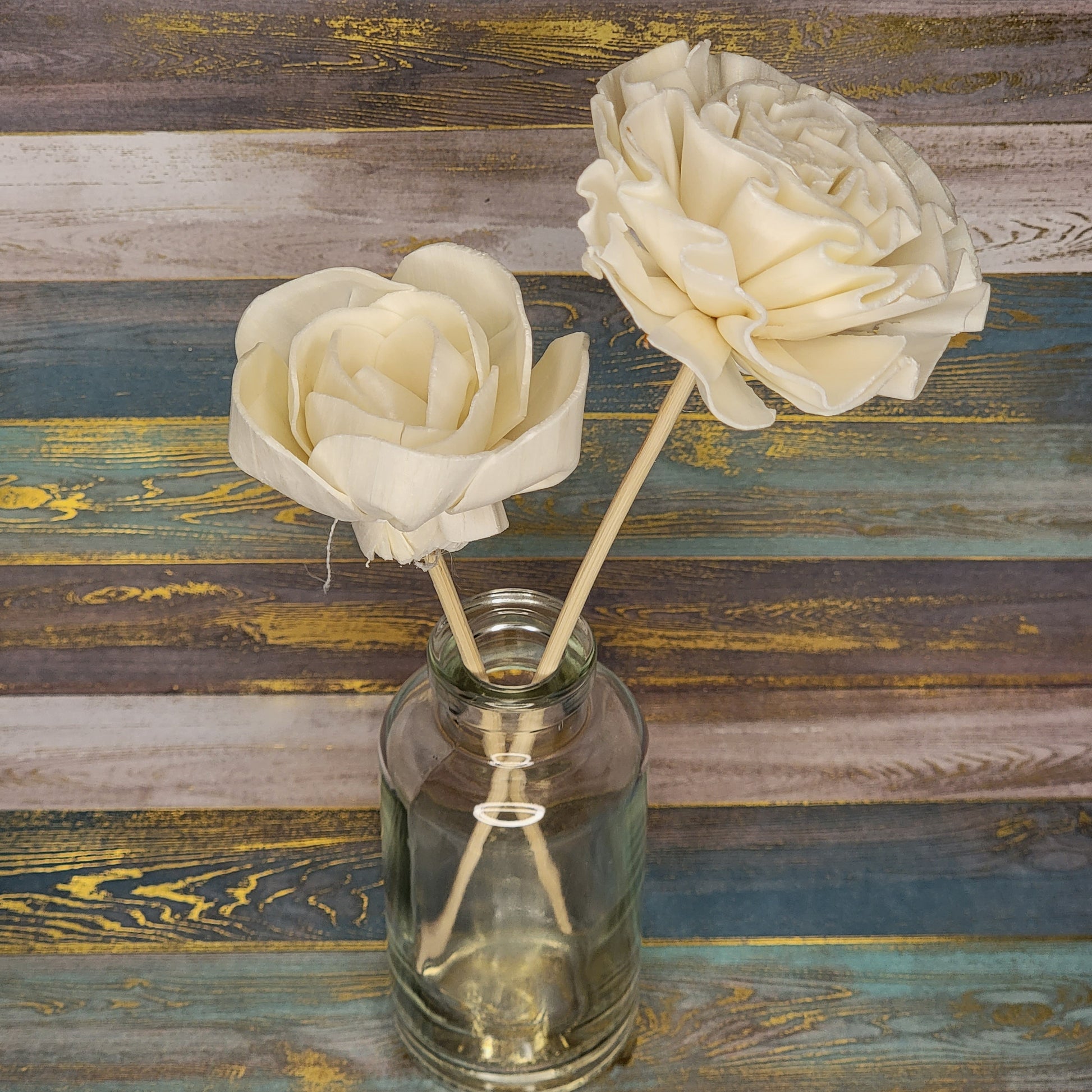 Two decorative cream roses in a glass jar on a rustic background.