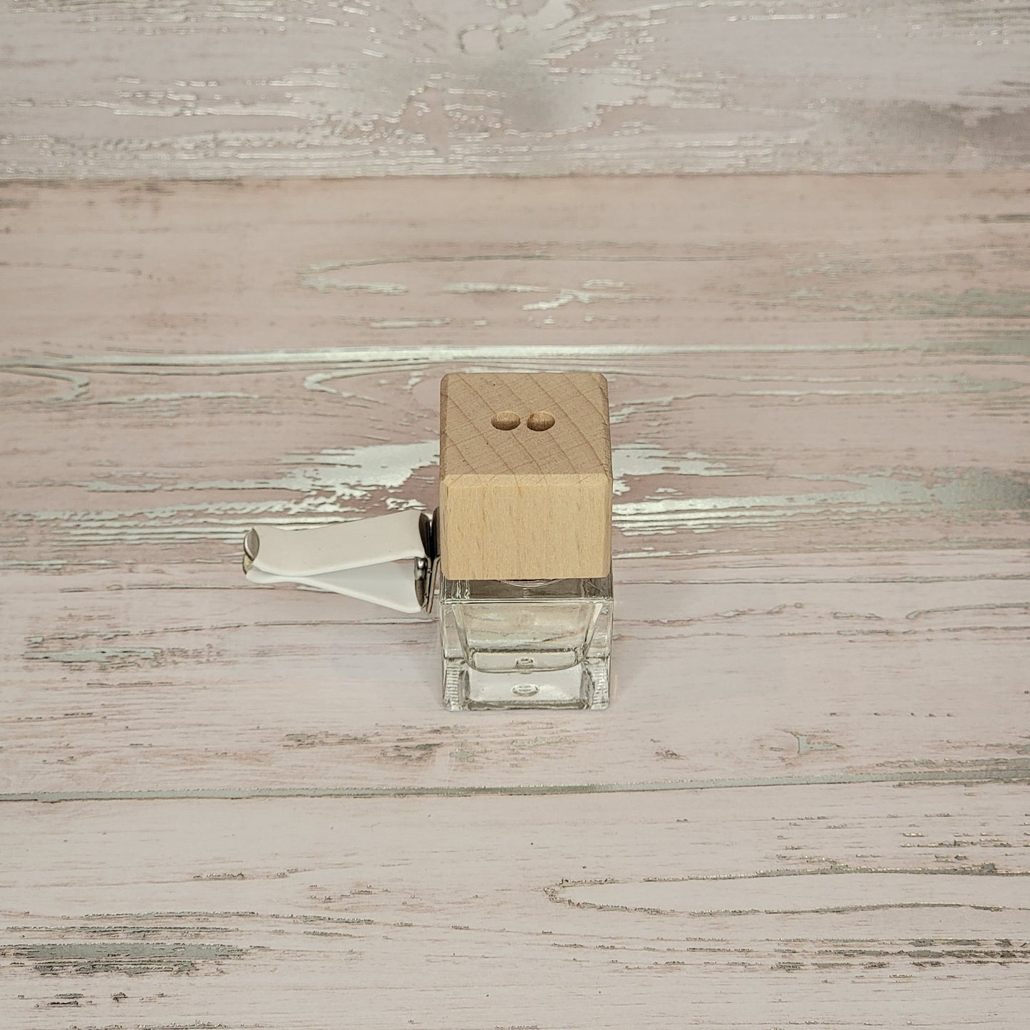 A small glass bottle with a wooden top and a lever on the side.