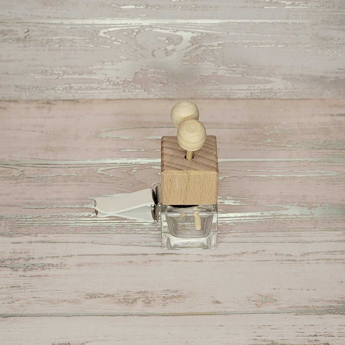 A top view of a small glass jar with a wooden lid and two wooden pegs on top.