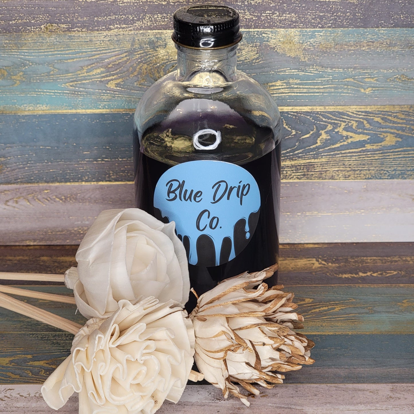 A bottle labeled 'Blue Drip Co.' surrounded by decorative flowers.