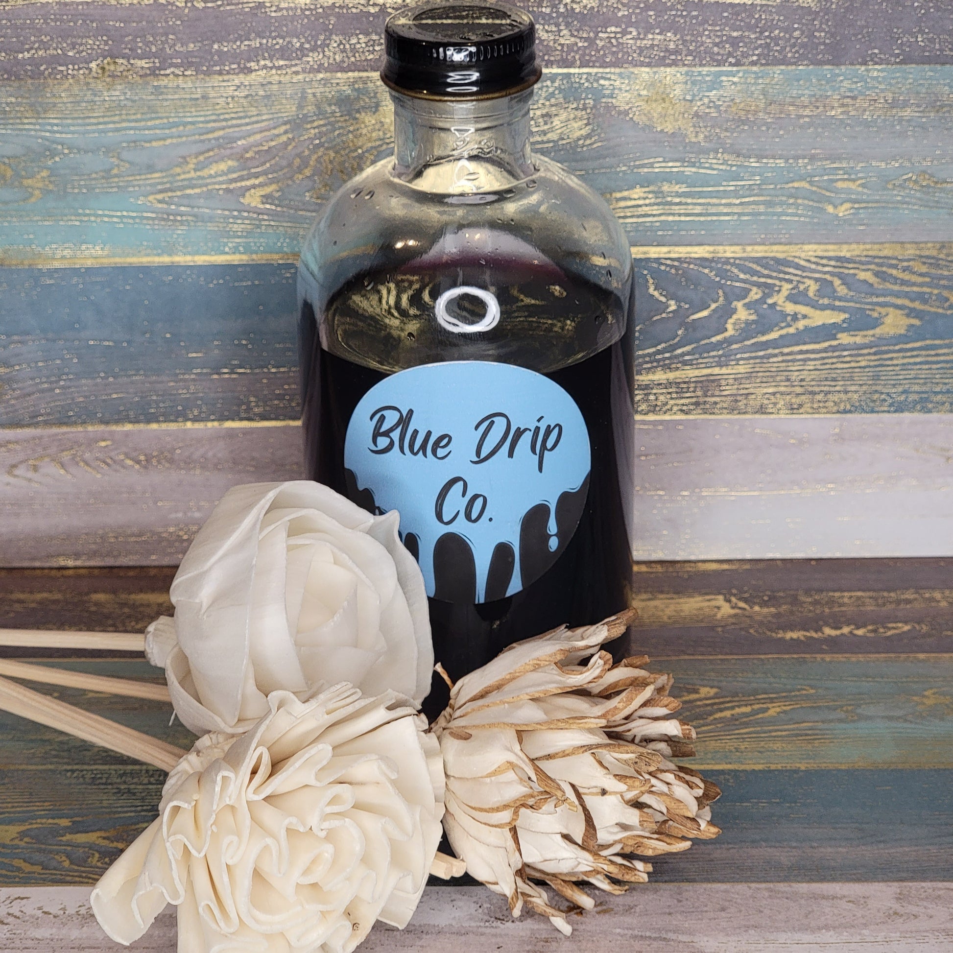 Bottle labeled 'Blue Drip Co.' with white decorative flowers beside it.