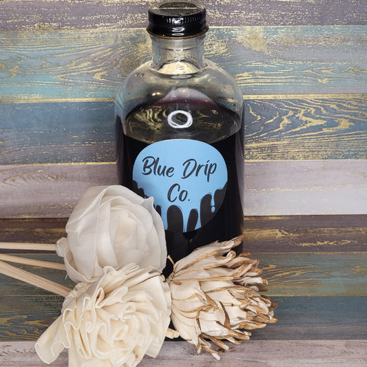 Bottle labeled 'Blue Drip Co.' with white decorative flowers beside it.