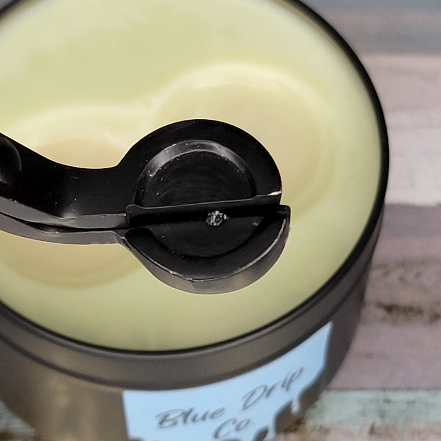 Close-up of a black scoop over a jar of creamy substance.