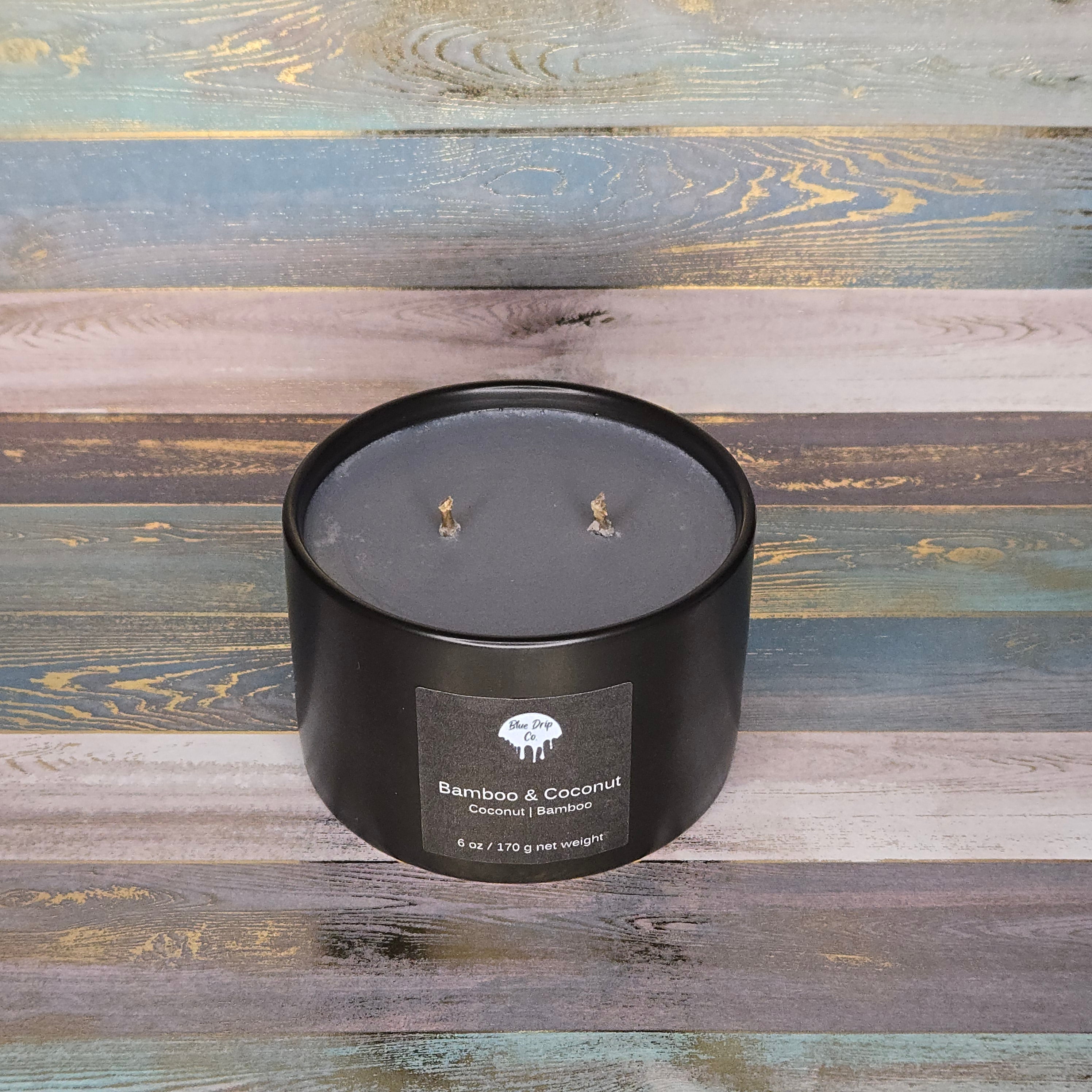 Black candle labeled 'Bamboo & Coconut' on a wooden background
