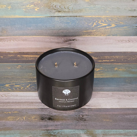 Black candle labeled 'Bamboo & Coconut' on a wooden background