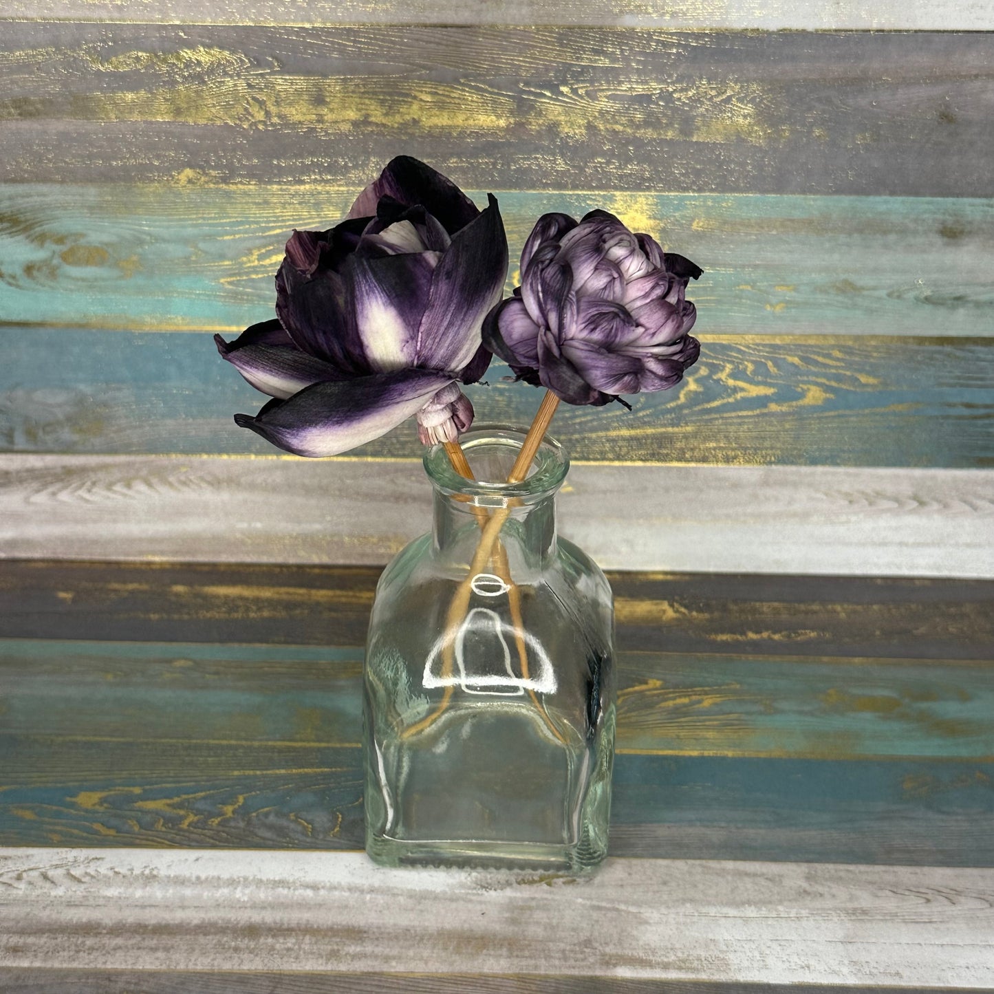 Glass vase with two purple flowers on a textured background