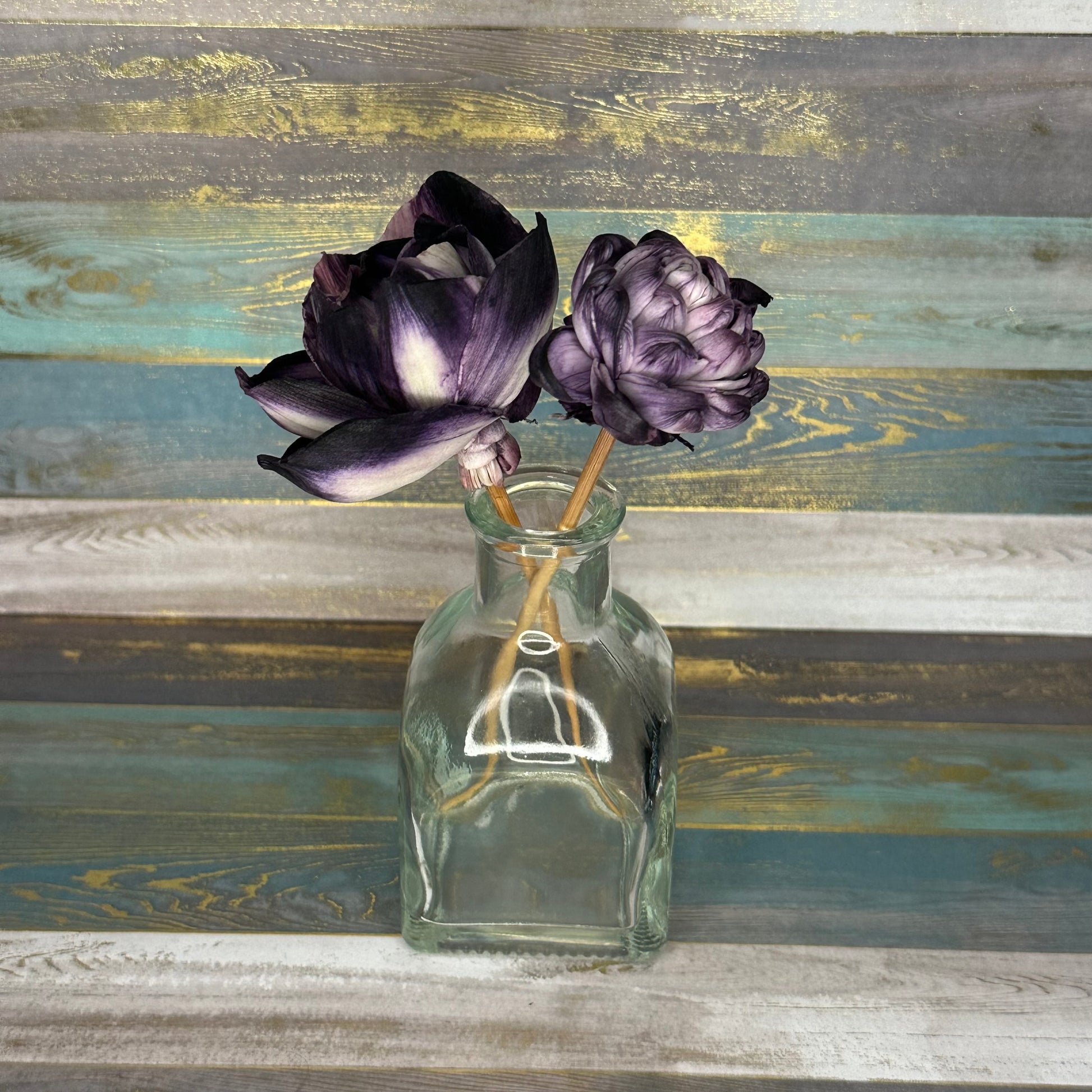 Glass vase with two purple flowers on a textured background