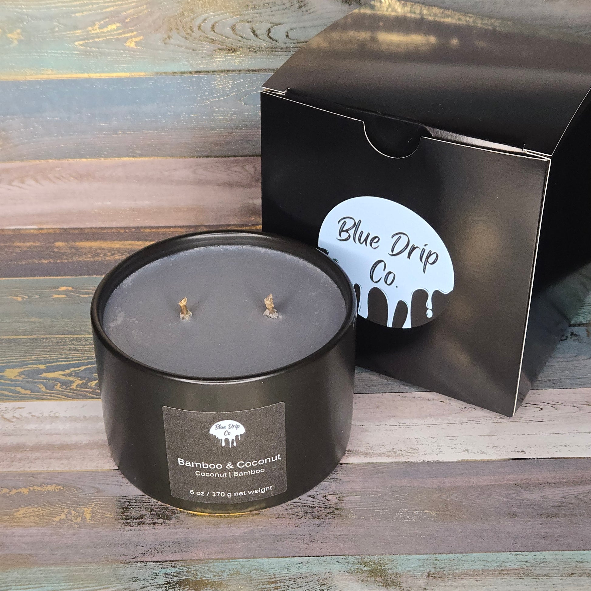 A black candle with three wicks, labeled 'Bamboo & Coconut', next to a box from Blue Drip Co.