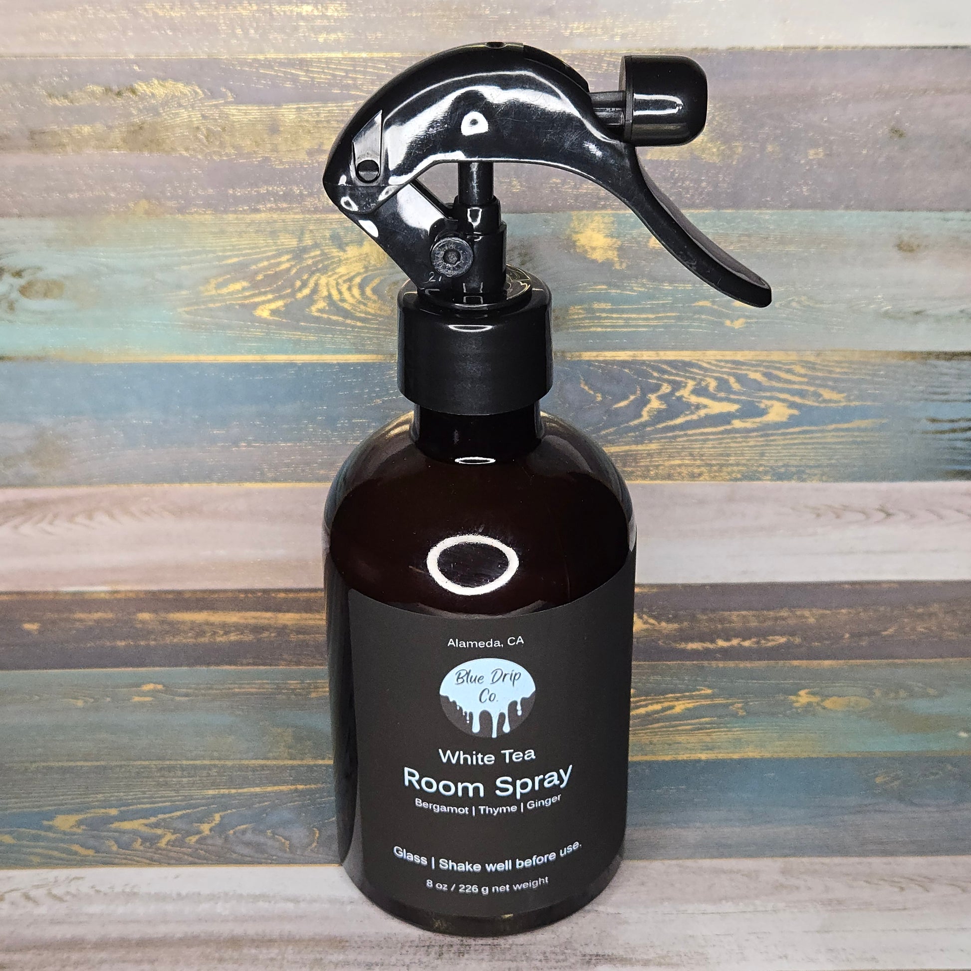 Bottle of White Tea Room Spray with a trigger sprayer on a wood background.