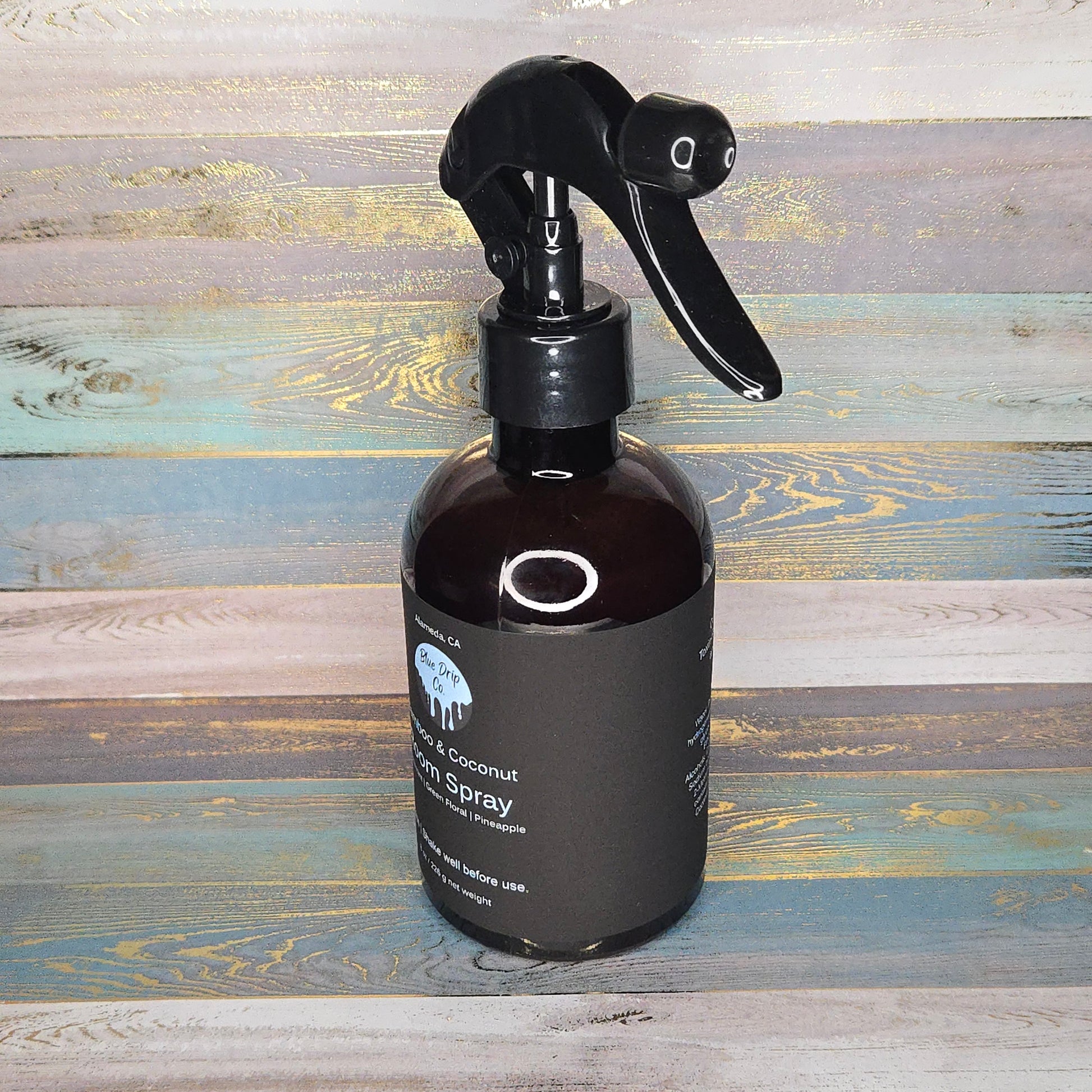 A dark bottle with a spray nozzle containing a coconut hair spray.