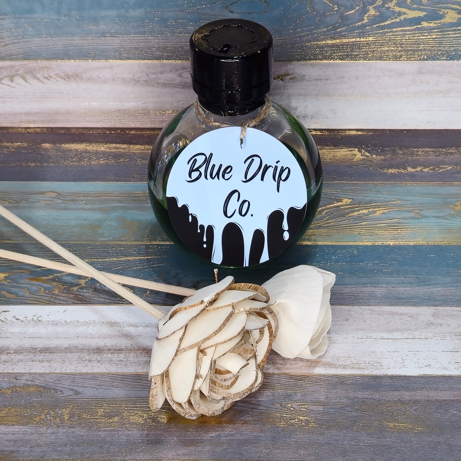 Bottle labeled 'Blue Drip Co.' next to a decorative white flower.